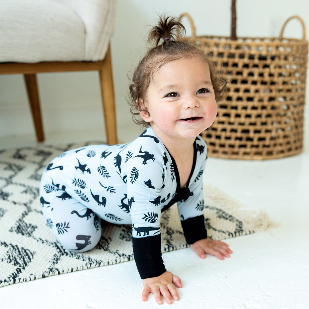 baby toddler girl in light blue bamboo pajamas with black dinosaur print